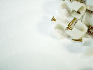 Cable clips fasteners and fixings lie on a textured white surface, perfect for DIY projects or...