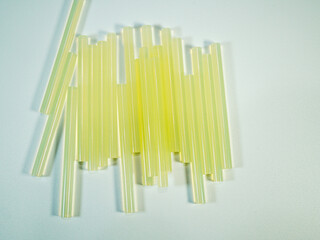 Numerous yellowish hot glue gun refills resting on a textured light surface suitable for crafts and...