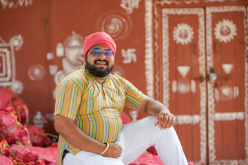 happy indian farmer at home sitting on crop bags