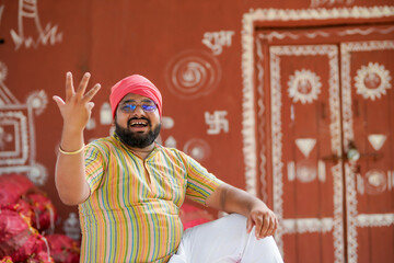 happy indian farmer at home sitting on crop bags