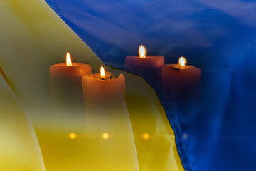 Candles on the background of the Ukrainian flag close-up, a symbol of mourning, grief and memory