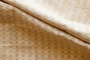 Beige fabric background with geometric checkered pattern with two folds in the middle, textile texture for interior