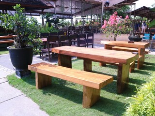 Set up a layout of wooden tables and chairs for an outdoor restaurant or cafe