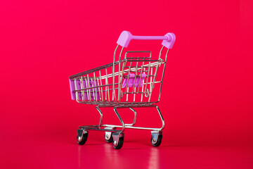Empty shopping trolley on red background. Space for text.