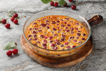 Cherry clafoutis French favorite is a sort of baked custard, studded with fresh cherries, and scented with vanilla close-up in a baking dish on the table. Horizontal