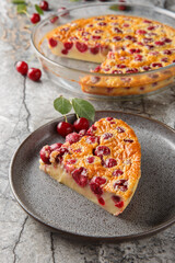pour-in clafoutis pie with cherries classic french dessert piece on plate close-up on table. Vertical