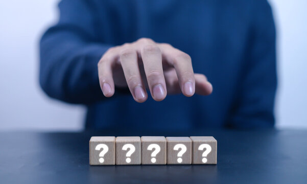 Man showing question mark on wooden cube. Concept of asking, thinking and wondering, answering, business FAQ 