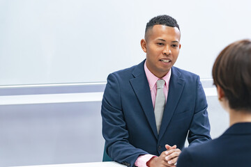 A Japanese female staff member interviewing a black male businessman