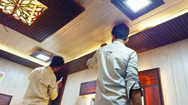 Installer snips wood at border of the ceiling panel