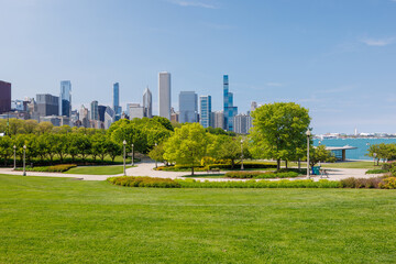 Sunny view of downtown Chicago with iconic skyscrapers rising above a lush green park meadow