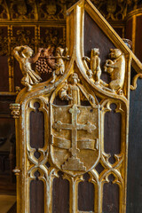 close-up of an intricately carved and gilded wooden panel, featuring a prominent heraldic shield