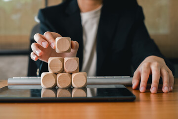 A professional arranging wooden blocks on a tablet, symbolizing business strategy, growth, and planning in a modern office environment.