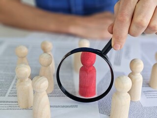 Analyzing group dynamics with wooden figurines under a magnifying glass in a workspace