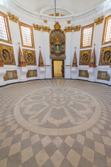 A grand, opulent interior with a central altar surrounded by ornate altarpieces