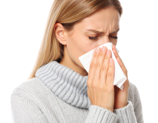 Young woman blowing nose into tissue while suffering from cold, flu or allergies