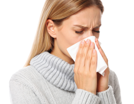Young woman blowing nose into tissue while suffering from cold, flu or allergies