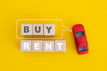 For Buy or Rent property concept, top view of wooden cube blocks with text, buy word inside speech bubble and red car on yellow background