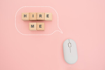 HIRE ME on wooden cube block inside speech bubble and white computer mouse on pink background