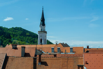 Scenic panorama view of historic city rooftops and church steeple in Slovenia, photographed through a window