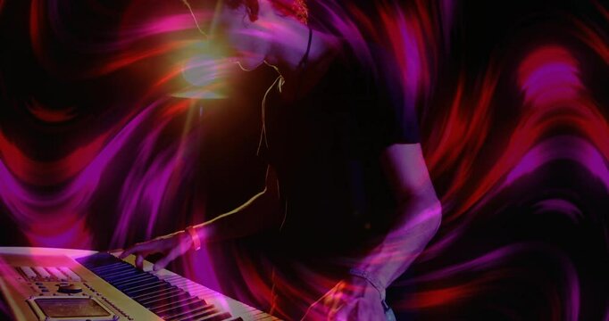 Musician pressing synth keys under warm backlight causing red magenta swirls in music performance