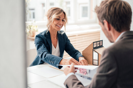 Real estate agent showing agreement to client at office - Powered by Adobe