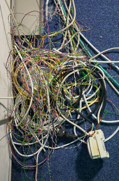Tangled old telephone wires in a server room with no people