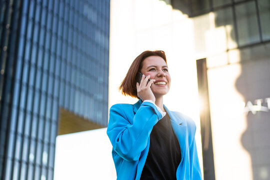 Happy businesswoman wearing blazer talking on smart phone