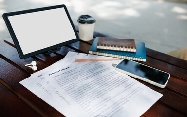 close up shot, digital tablet and business contract, mobile phone, notebook on wooden table in park, working outside make business contract online via tablet