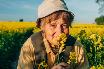 Senior woman enjoying a spring day in a rapeseed field while backpacking