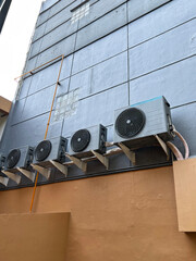 Multiple outdoor air conditioning units, also known as condensers, mounted on the side of a...