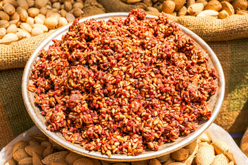 A vibrant spice blend in a metal bowl, surrounded by almonds and nuts in burlap sacks—perfect for...