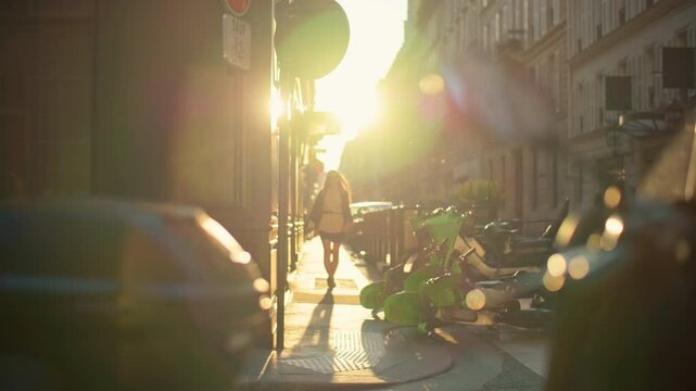 Woman tourist walks through romantic streets of Paris at sunset. Beautiful girl walks along historic street with beautiful architecture in the capital of France.