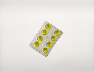 A yellow pill is on a white background. There are six pills in total. The pill is in the middle of...