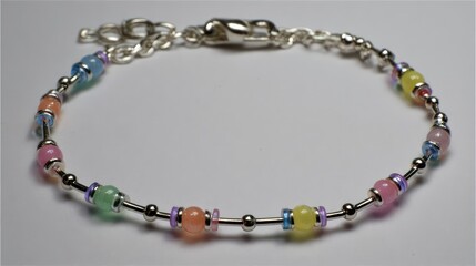 Bright and simple silver children's bracelet featuring pastel beads laid on white