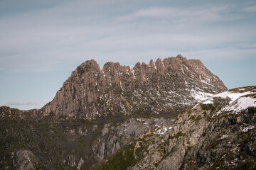 A snow-covered Cradle Mountain in Tasmania during winter, featuring rugged peaks and dramatic scenery under a clear sky, perfect for nature, adventure, travel, and winter landscape themes
