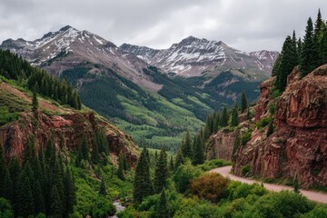 Mountain pass with red rock cliffs, snow-capped peaks, lush green valleys