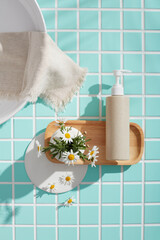 Bathroom layout with wooden tray, flowers, white dish and pump bottle on blue tile. Clear space on...