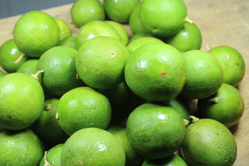 A close up pile of fresh green limes with natural texture on a wooden background