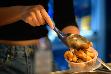 Take away stir fry food being served into a container by hand