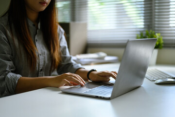Young entrepreneur typing on laptop, working remotely or managing business tasks in a calm workspace