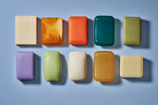 Flat lay still life rows of various multicolored homemade soap bars on blue background
