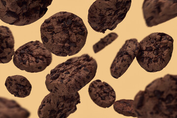 Chocolate chip cookies falling against yellow background
