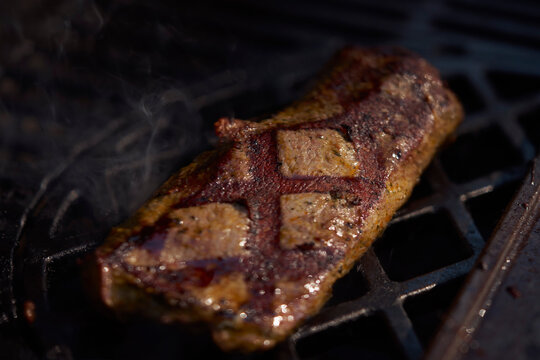 Still life close up of grilled saddle of lamb with sear marks on barbecue grill
