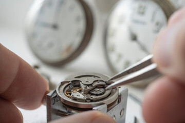 Professional watchmaker repairer working on an old vintage pocket watch in a workshop.