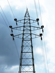 Tall steel electricity transmission tower against cloudy sky