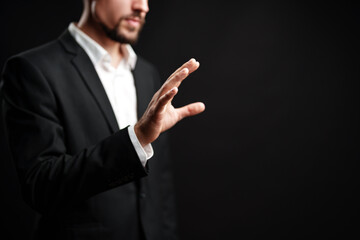 Professional man gesturing with hand against dark background in a corporate setting during...