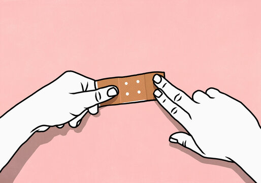 Point of view from above of hands placing bandage on pink background
