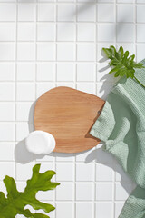 Bathroom scene with wooden tray, towel and round sponge placed on white tiles. Soft light and...