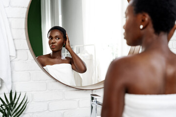 Young woman examines her reflection in a mirror while getting ready in a serene bathroom environment