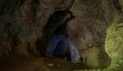 A hiker with a flashlight exploring the deep interior of Szeleta Cave, highlighting the impressive...